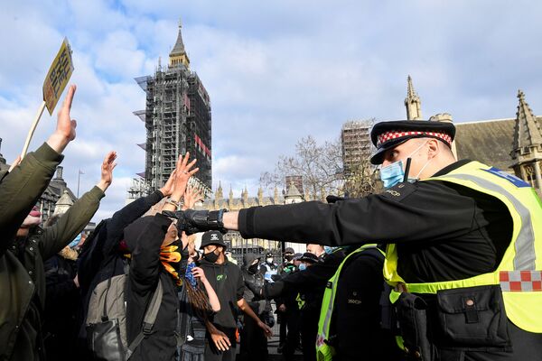 Unos manifestantes levantan las manos mientras se enfrentan a los agentes de policía durante una protesta en Londres (Reino Unido). - Sputnik Mundo