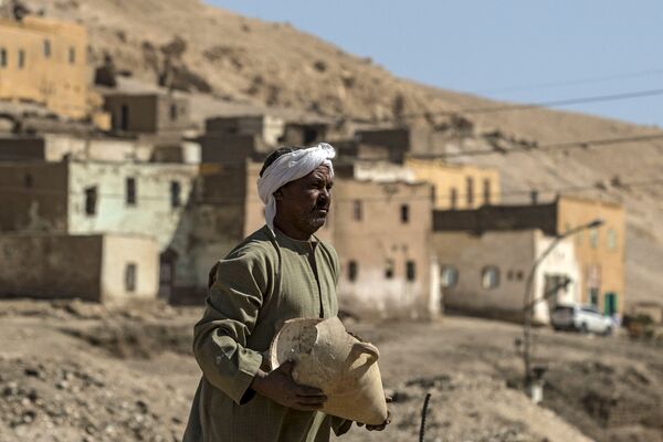 Un trabajador sostiene una vasija en el asentamiento arqueológico. - Sputnik Mundo