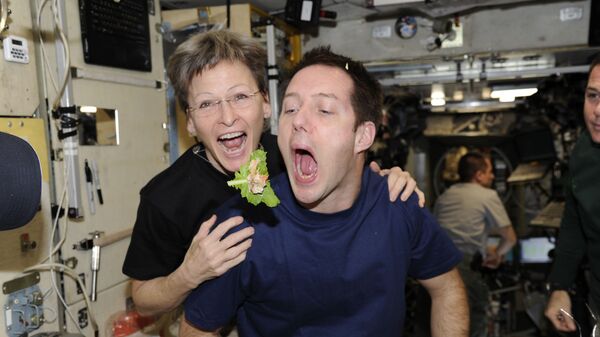 El astronauta francés Thomas Pesquet y la astronauta de la NASA Peggy Whitson a bordo de la EEI con una hoja de lechuga - Sputnik Mundo