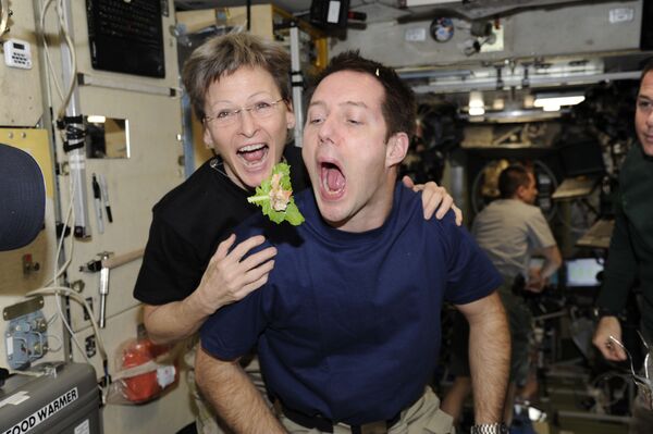 El astronauta francés Thomas Pesquet y la astronauta de la NASA Peggy Whitson a bordo de la EEI con una hoja de lechuga.   - Sputnik Mundo