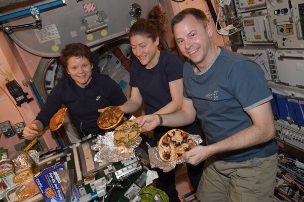 El astronauta estadounidense Nick Hague (a la derecha) compartió en su cuenta de Twitter una imagen de una espontánea fiesta de pizza en la EEI. &quot;Hacer pizza en el espacio es similar a hacer pizza en la Tierra, la única diferencia es que nuestros hornos son un poco diferentes y nuestra pizza puede flotar&quot;, explicó.  - Sputnik Mundo