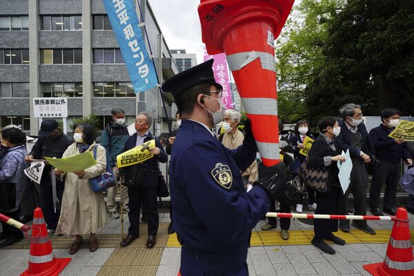 Un policía y varios manifestantes en contra de los planes del Gobierno japonés. - Sputnik Mundo