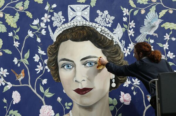 Unos obreros instalan un mural de Frederick Wimsett que representa a Isabel II en la víspera de su 90 cumpleaños, en el centro de Londres. - Sputnik Mundo