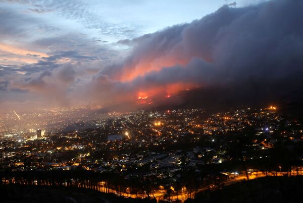 Las llamas de un incendio forestal iniciado en las laderas de la montaña de la Mesa se acercan a las residencias en la Ciudad del Cabo (Sudáfrica) el 19 de abril. - Sputnik Mundo