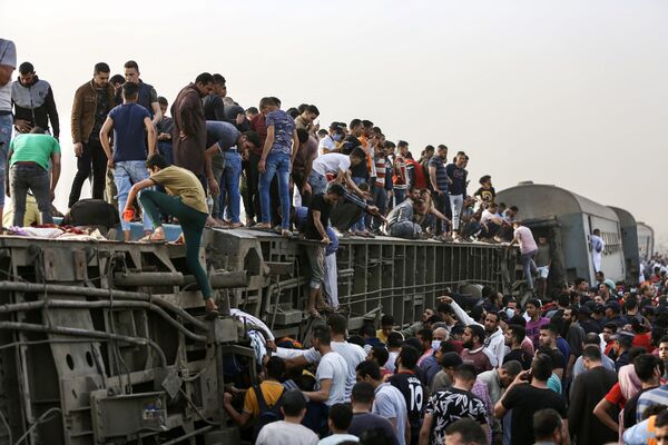 Unas personas suben a un vagón volcado en el lugar de un accidente de tren en la ciudad egipcia de Toukh. - Sputnik Mundo