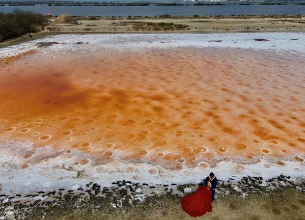 Una pareja de novios posa para una fotógrafo junto a un campo de sal de color rosa ubicado en la ciudad china de Tainan.El fenómeno fue provocado por la falta de lluvia. - Sputnik Mundo