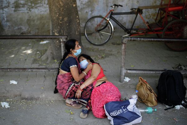 Una mujer sostiene a su familiar en la calle en medio de la crisis sanitaria en la India. - Sputnik Mundo