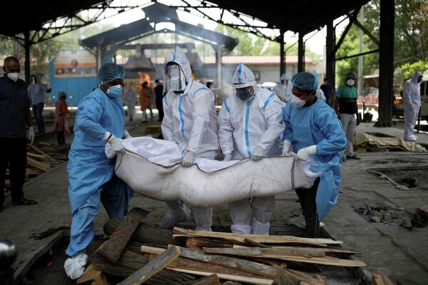 Varias personas con trajes de bioseguridad evacúan a las personas que fallecieron por coronavirus en la India. - Sputnik Mundo