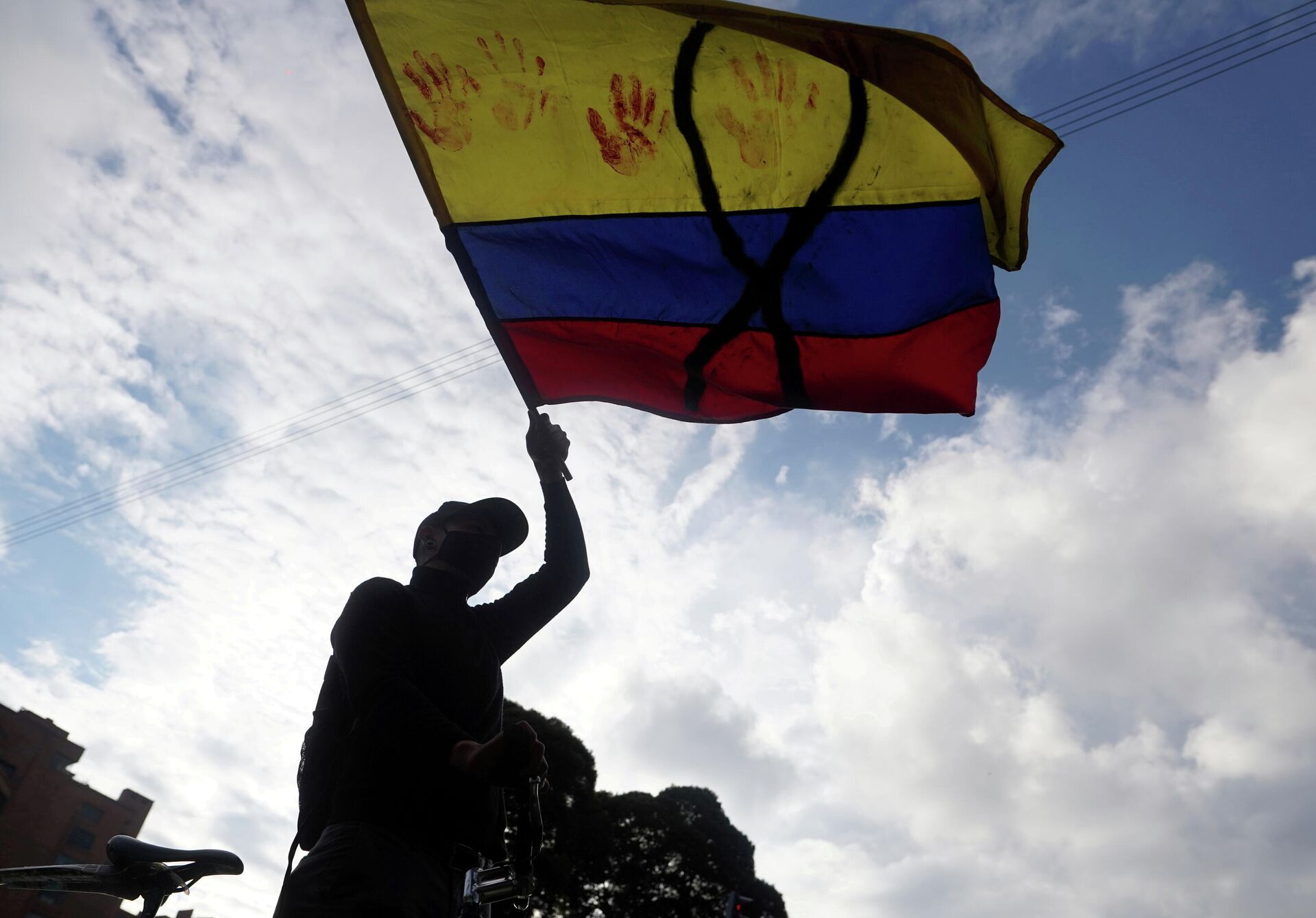 Un manifestante con una bandera de Colombia con un lazo negro y manchas rojas - Sputnik Mundo, 1920, 11.05.2021