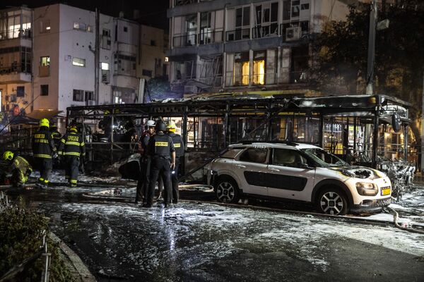 Poco después de la destrucción del edificio, los grupos palestinos dijeron que respondieron con 130 cohetes contra Tel Aviv. En la foto: los bomberos en el lugar donde impactó un cohete palestino en la ciudad de Holon, cerca de Tel Aviv.  - Sputnik Mundo