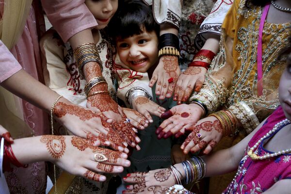 Unas mujeres musulmanas muestran las manos pintadas con alheña —un tinte natural rojizo típico de algunos países árabes— en honor al Eid al-Fitr en Peshawar (Pakistán).  - Sputnik Mundo