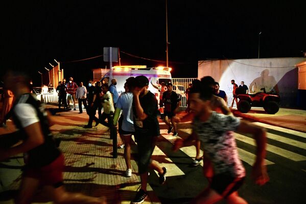 Los migrantes comenzaron a llegar a Ceuta a las 02:00 hora local —medianoche GMT— del 17 de mayo. En la foto: migrantes corren tras su llegada a la playa del Tarajal, el 17 de mayo de 2021. - Sputnik Mundo