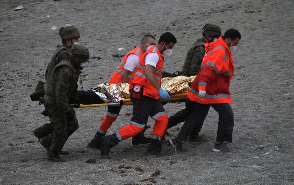 Según informaciones preliminares, al menos una persona murió durante la travesía.En la foto: un hombre es llevado en una camilla por miembros del equipo de emergencia y militares españoles en la frontera hispano-marroquí. - Sputnik Mundo