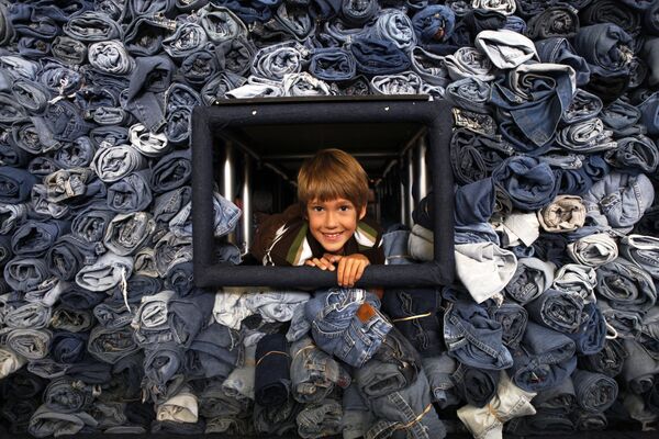 Los primeros jeans fueron producidos y vendidos en 1850 por Levi Strauss, quien emigró a Estados Unidos desde Alemania tres años antes. Los primeros pantalones se hicieron de lona y tenían muchos bolsillos.En la foto: Un niño posa al lado de 33.088 pares de jeans recolectados por la revista National Geographic Kids para ser reciclados y convertidos en material aislante para viviendas en Washington. - Sputnik Mundo