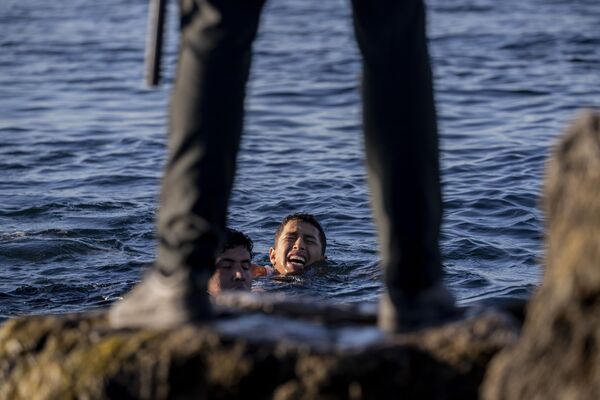 Un representante de la Guardia Civil española con unos inmigrantes en la costa de Ceuta, cerca de la frontera hispano-marroquí.  - Sputnik Mundo