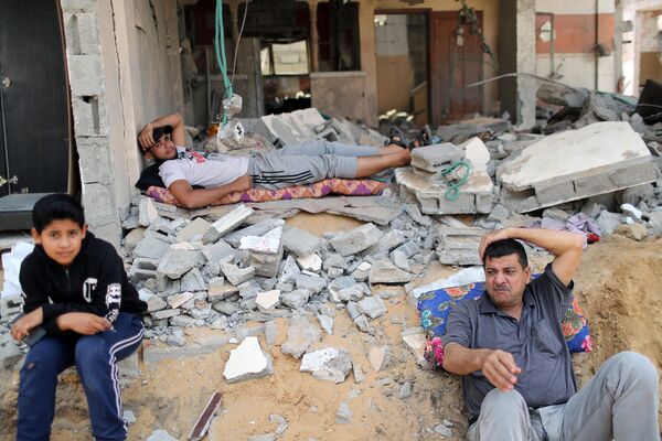 Unos palestinos en su casa destruida por un misil, en Beit Hanun, al noreste de Gaza. - Sputnik Mundo
