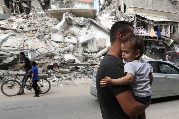 Unos palestinos pasan por unos edificios destruidos durante el conflicto entre Israel y Hamás. - Sputnik Mundo