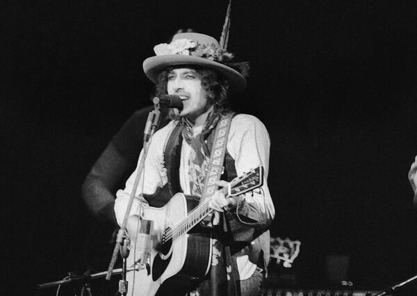 A finales de 1963, Dylan sintió que se había convertido en un prisionero de su propia imagen. En 1965, dejó en shock a los aficionados al folk acústico al tocar la guitarra eléctrica en el Newport Folk Festival, algo que entró en la historia de la música como &quot;la controversia eléctrica de Bob Dylan&quot;. En la foto: un concierto de Bob Dylan en el Madison Square Garden, en 1975. - Sputnik Mundo