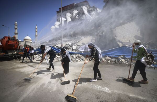 Unos funcionarios municipales y unos voluntarios palestinos limpian los escombros en la ciudad de Gaza tras unos ataques aéreos israelíes. - Sputnik Mundo