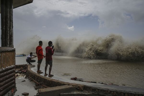 Unos lugareños fotografían las olas rompiendo a lo largo de la costa del golfo de Bengala en Digha, la India, durante el paso del ciclón Yaas por la región. - Sputnik Mundo