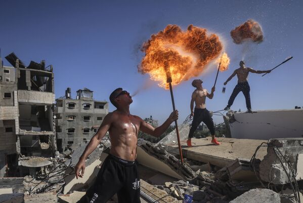 Unos miembros del equipo palestino Bar Woolf de Gaza realizan un espectáculo de fuego en las ruinas de un edificio destruido por los ataques aéreos israelíes. - Sputnik Mundo