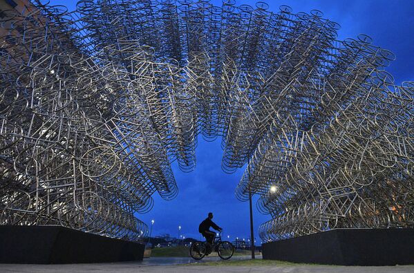 Hoy en día, el mundo está experimentando un nuevo bum de la bicicleta. En la foto: un hombre pasa con su bicicleta delante de una instalación artística denominada &#x27;Forever Cycles&#x27; creada por el artista chino Ai Weiwei en Río de Janeiro en 2019.  - Sputnik Mundo