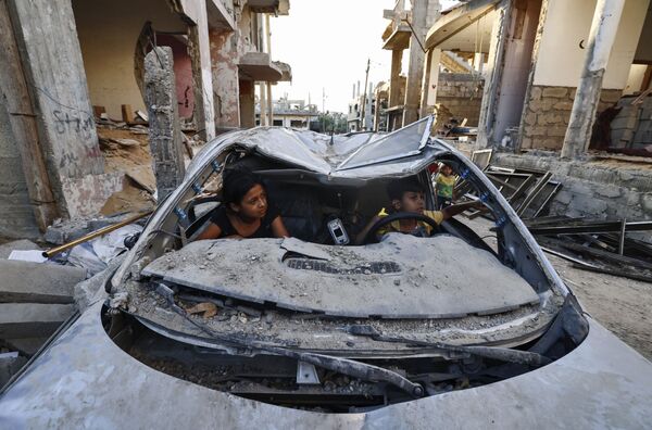 Dos niños palestinos juegan dentro de un coche dañado por los ataques aéreos israelíes en Beit Hanun, Franja de Gaza. - Sputnik Mundo