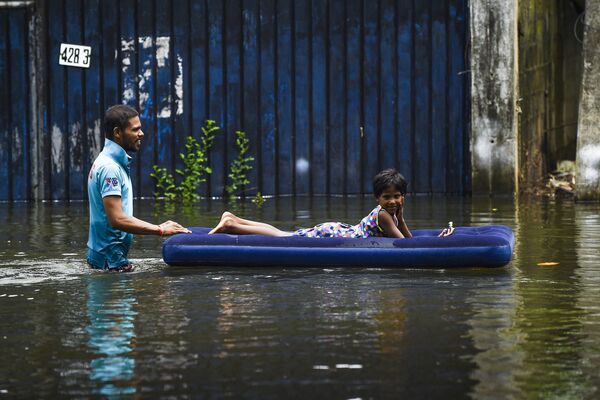 Un hombre transporta a un niño por una calle inundada en Colombo, Sri Lanka. - Sputnik Mundo