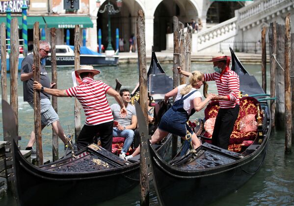 Los gondoleros venecianos ayudan a los turistas a subir a las góndolas. - Sputnik Mundo