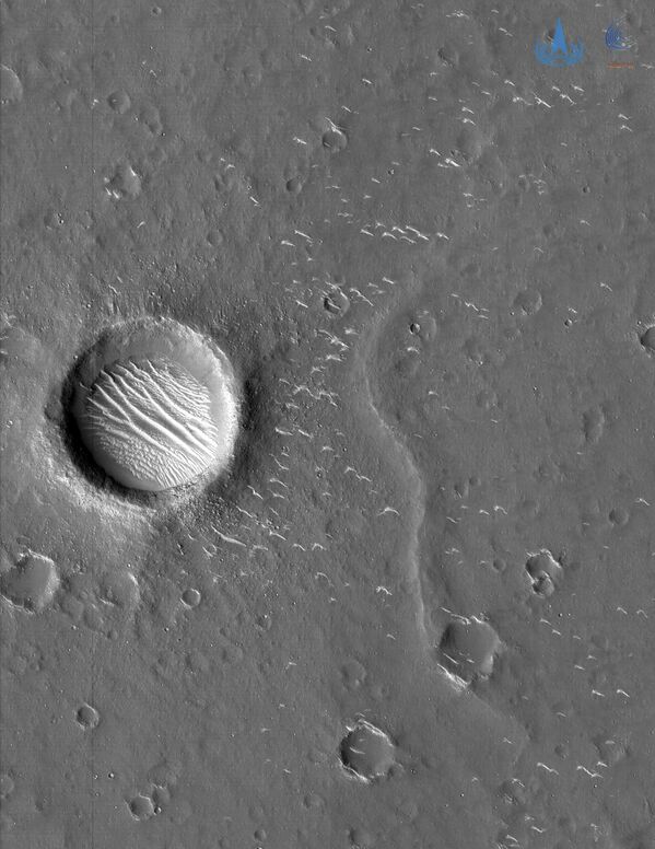 Además, la sonda tomó dos fotografías en blanco y negro de alta resolución a una distancia de entre 330 y 350 kilómetros de la superficie de Marte. En ella es posible ver pequeños cráteres, crestas y dunas. El diámetro del cráter más grande (en la foto) se estima en unos 620 metros. - Sputnik Mundo