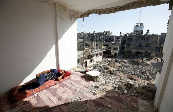 La  ONU informa que alrededor de 800.000 personas en la Franja de Gaza no tienen acceso permanente al agua potable, ya que casi un 50% del sistema de abastecimiento de aguas fue dañado por los ataques aéreos israelíes. En la foto: un palestino duerme en su hogar  destruido. - Sputnik Mundo