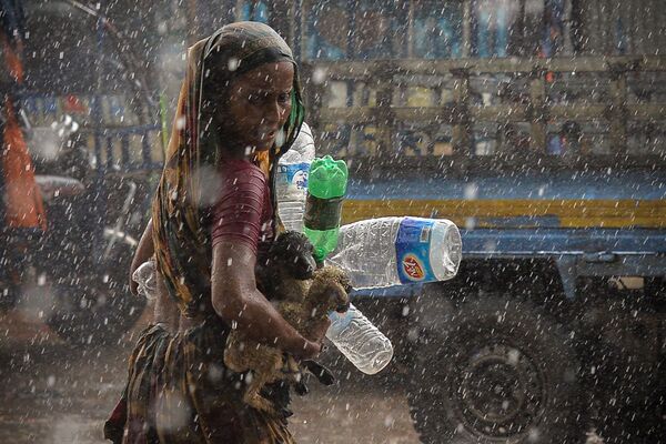 Una mujer bajo la lluvia torrencial en la ciudad de Daca, Bangladés. - Sputnik Mundo