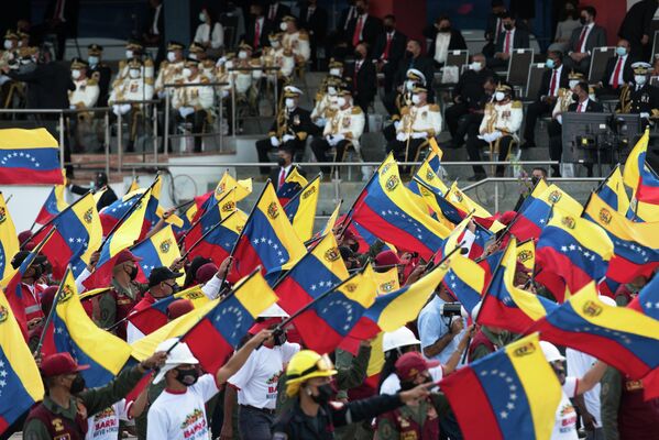 La sangrienta guerra por la independencia duró diez años y terminó en 1821. En la foto: miembros de la Guardia Nacional Bolivariana alzan banderas nacionales durante el desfile. - Sputnik Mundo