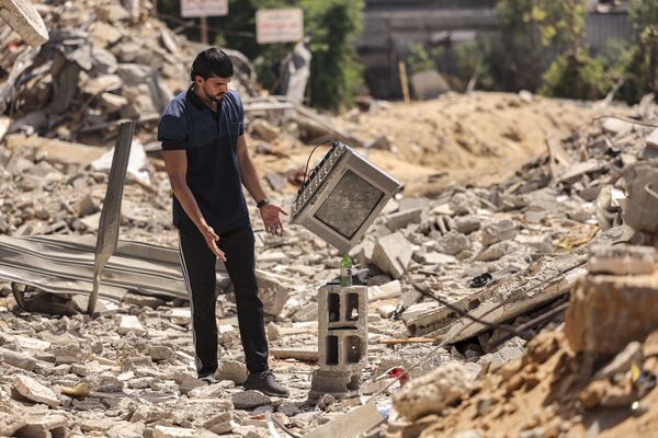 El artista palestino Mohammed Shenbari muestra su equilibrio en las ruinas de las casas en la Franja de Gaza destruidas por los ataques aéreos israelíes.   - Sputnik Mundo
