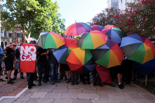 Manifestantes sostienen paraguas de arcoiris mientras protestan contra los ministros de Finanzas de los países del G20 y sus medidas políticas, en Venecia (Italia), el 10 de julio de 2021 - Sputnik Mundo