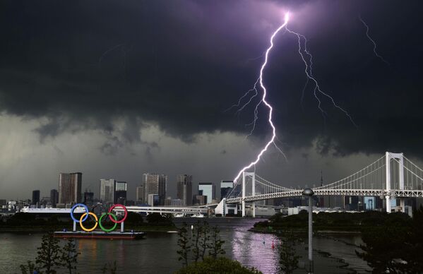 Un rayo alcanza el puente Rainbow Bridge y el monumento de los aros olímpicos en Tokio, Japón. - Sputnik Mundo