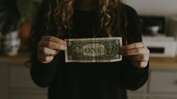 Una mujer sostiene un billete de un dólar () - Sputnik Mundo