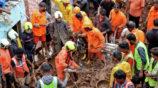 Los trabajadores de rescate retiran escombros mientras buscan sobrevivientes después de que una casa colapsara debido al deslizamiento de tierra causado por fuertes lluvias en Bombay, la India, el 18 de julio - Sputnik Mundo