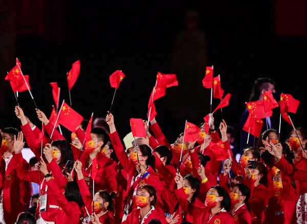 Miembros de la delegación de China ondean banderas al entrar al Estadio Olímpico. - Sputnik Mundo