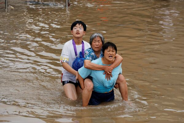Más de 157.000 personas necesitan asistencia de emergencia. En la foto: residentes locales cruzan una calle inundada en Zhengzhou, provincia de Henan. - Sputnik Mundo