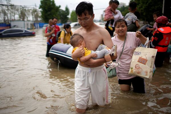 Los lugareños cruzan una calle inundada en Zhengzhou. - Sputnik Mundo
