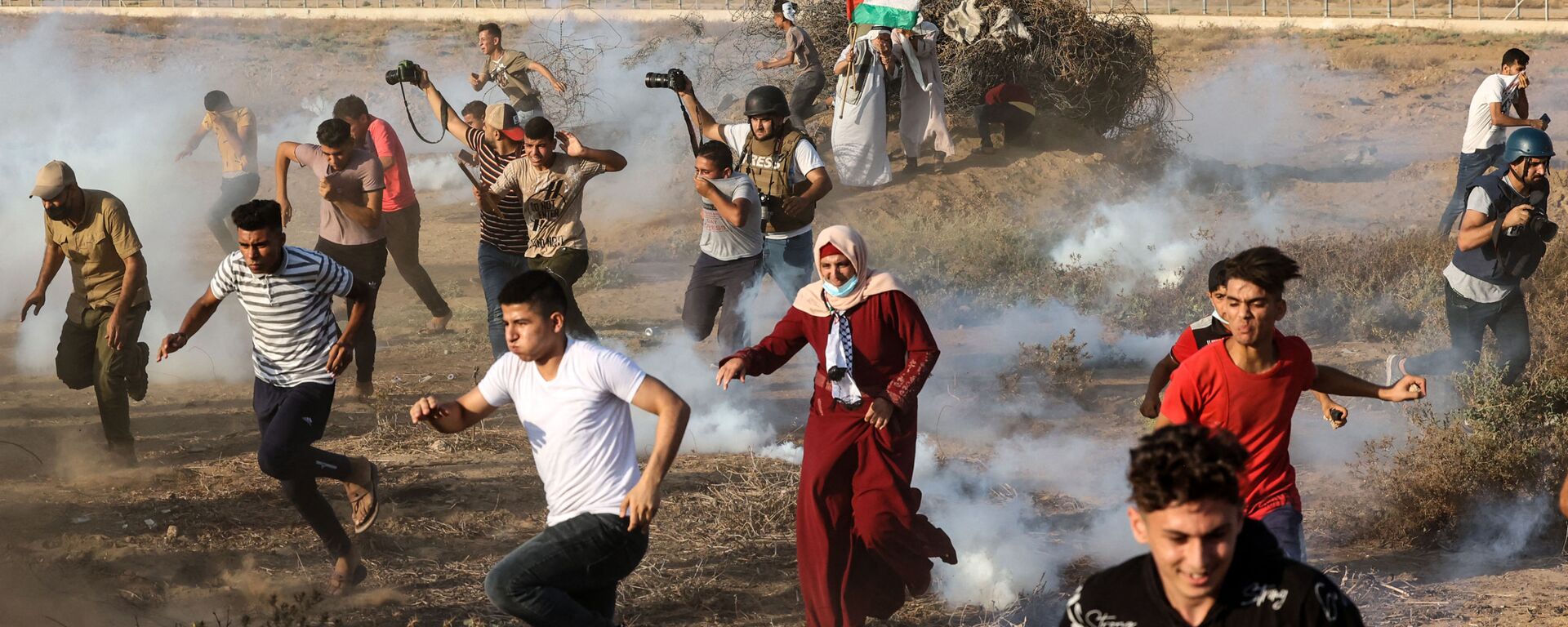 Палестинские демонстранты и журналисты бегут от слезоточивого газа во время акции протеста на юге сектора Газа - Sputnik Mundo, 1920, 13.09.2021