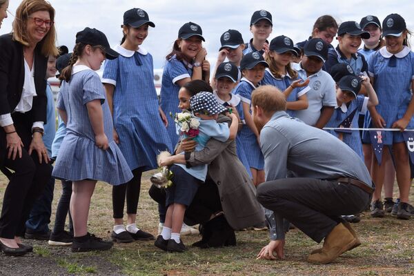 El uniforme escolar en Australia es similar al uniforme escolar británico tradicional, pero es más abierto y ligero, y con un tocado.En la foto: escolares australianos con el príncipe Harry y su esposa Meghan en el aeropuerto de Dubbo, 2018. - Sputnik Mundo