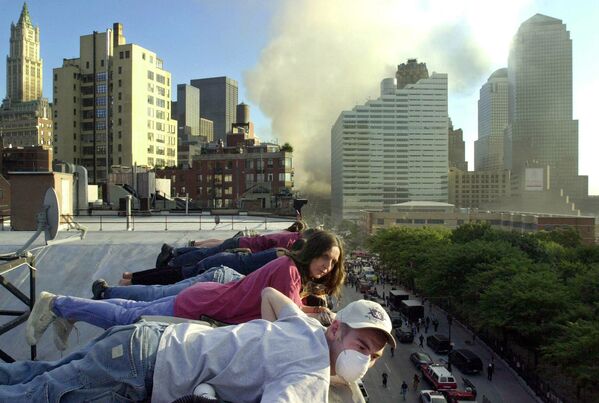 El vuelo 175 de United Airlines chocó contra la torre sur del WTC a las 9:03 (hora local) entre los pisos 78 y 85. En la foto: la gente observa la operación de rescate después del ataque terrorista del 11 de septiembre desde el techo de una casa en Greenwich St. - Sputnik Mundo