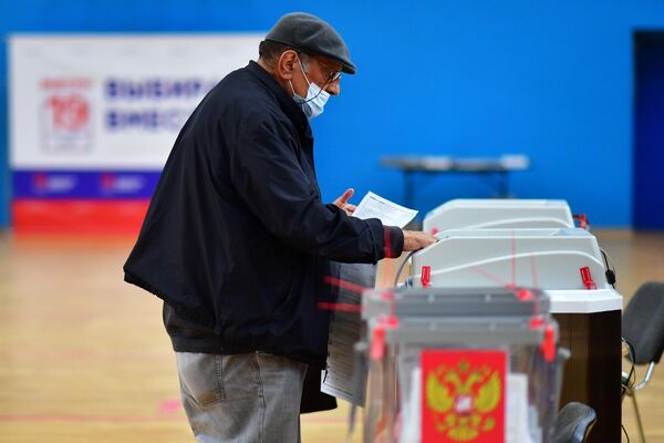 Un hombre vota en uno de los colegios electorales de Moscú. - Sputnik Mundo