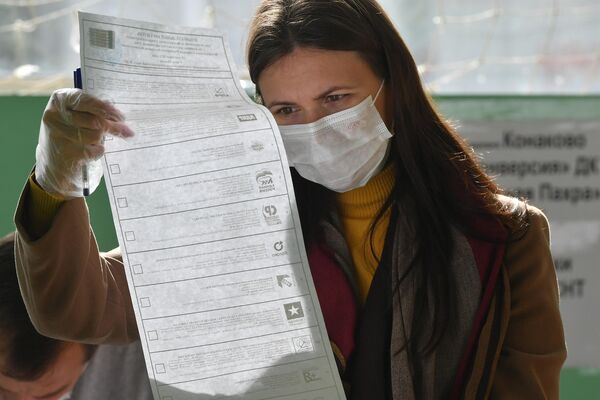 Una mujer busca su candidato en la papeleta electoral. - Sputnik Mundo