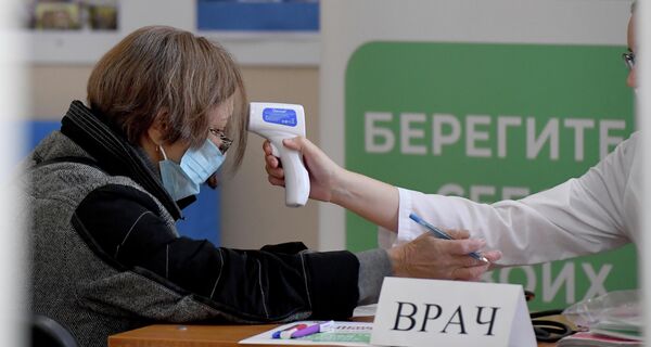 Medición de la temperatura de una ciudadana antes de entrar en el colegio electoral. - Sputnik Mundo