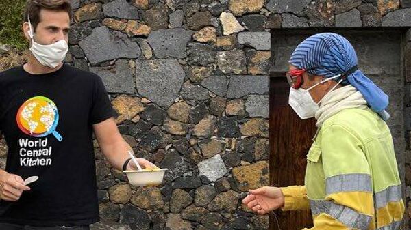 Un voluntario de World Central Kitchen ofreciendo comida a uno de los trabajadores del volcán de La Palma - Sputnik Mundo