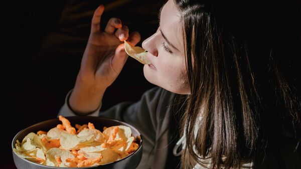 Una mujer comiendo comida chatarra - Sputnik Mundo