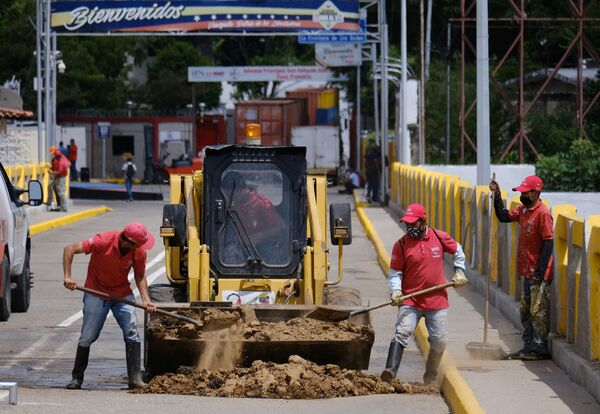 Unos trabajadores llenan un agujero que dejó uno de los contenedores en el puente Simón Bolívar. - Sputnik Mundo